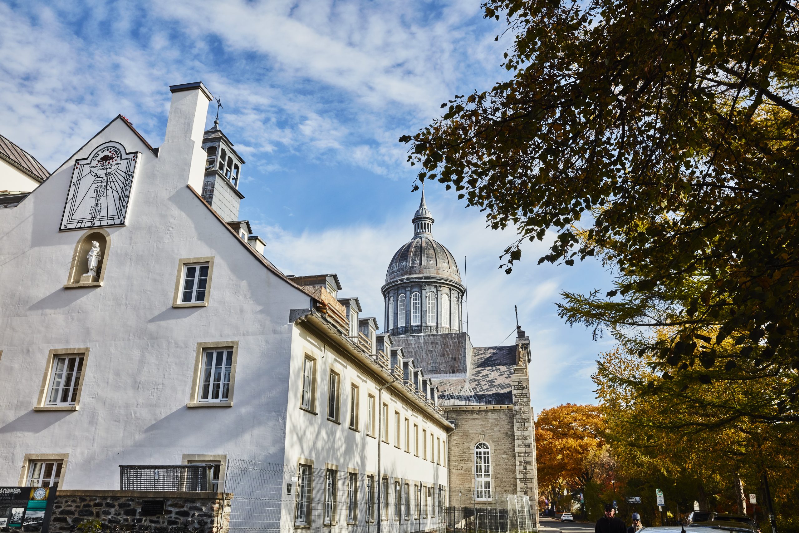 Édifice historique avec un dôme en Mauricie, encadré par des feuilles d'automne et un ciel bleu.
