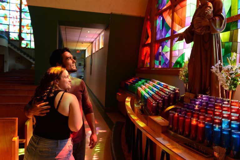 Couple devant un mur de cierges colorés à l'Ermitage Saint-Antoine.