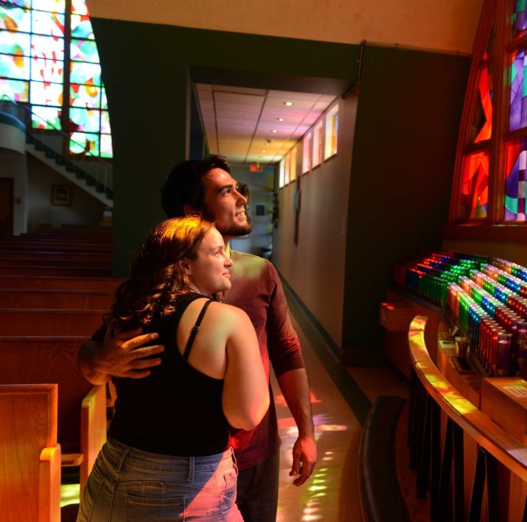 Couple devant un mur de cierges colorés à l'Ermitage Saint-Antoine.