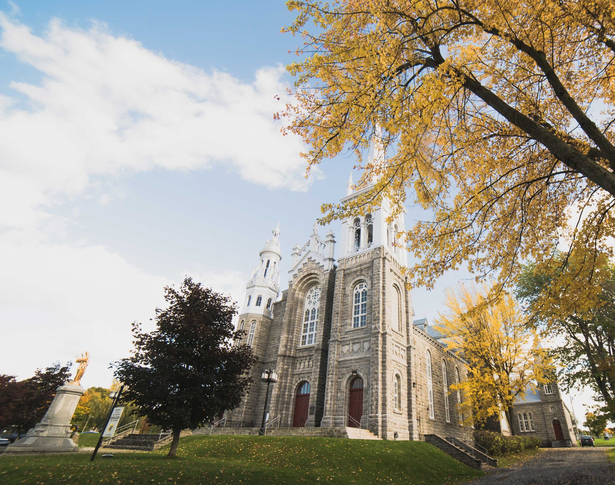 Devanture de l'Église Saint-Vital de Lambton, avec un arbre aux feuilles doré en avant-plan.