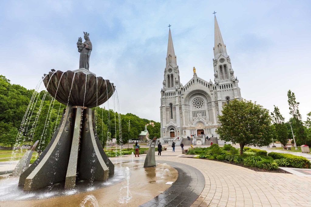Sanctuaire Sainte-Anne-de-Beaupré vue de l'extérieur, avec une fontaine à l'avant-plan.