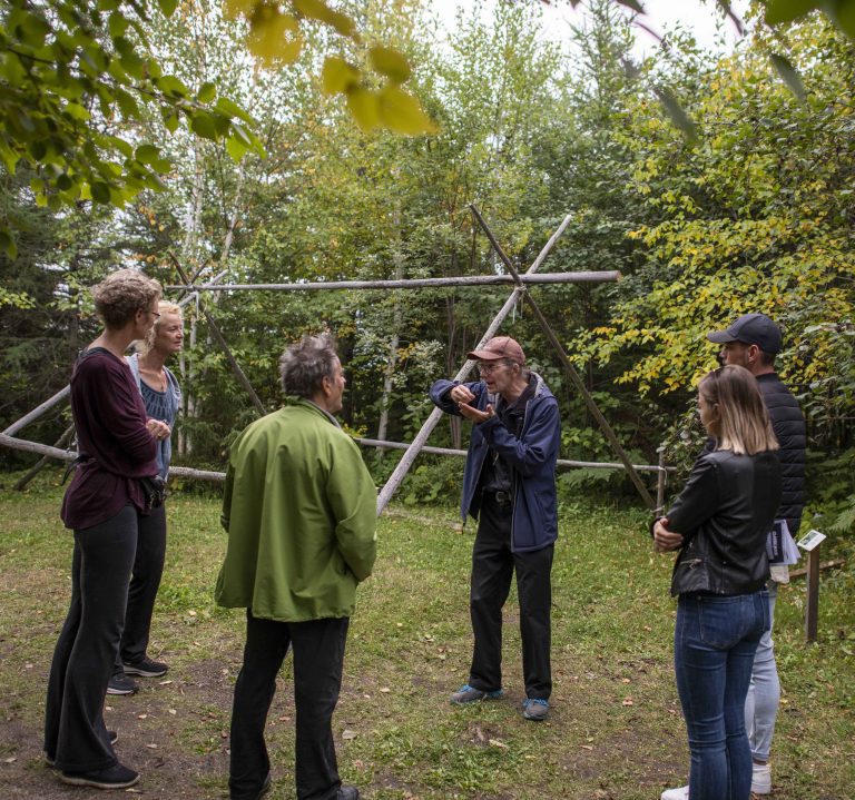 Groupe de personnes en train d'écouter les explications d'un guide sur le sentier d'interprétation du Musée ilnu de Mashteuiatsh